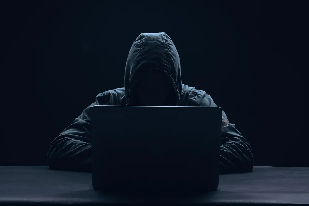 Imagem meramente ilustrativa de hacker com capuz em fundo preto