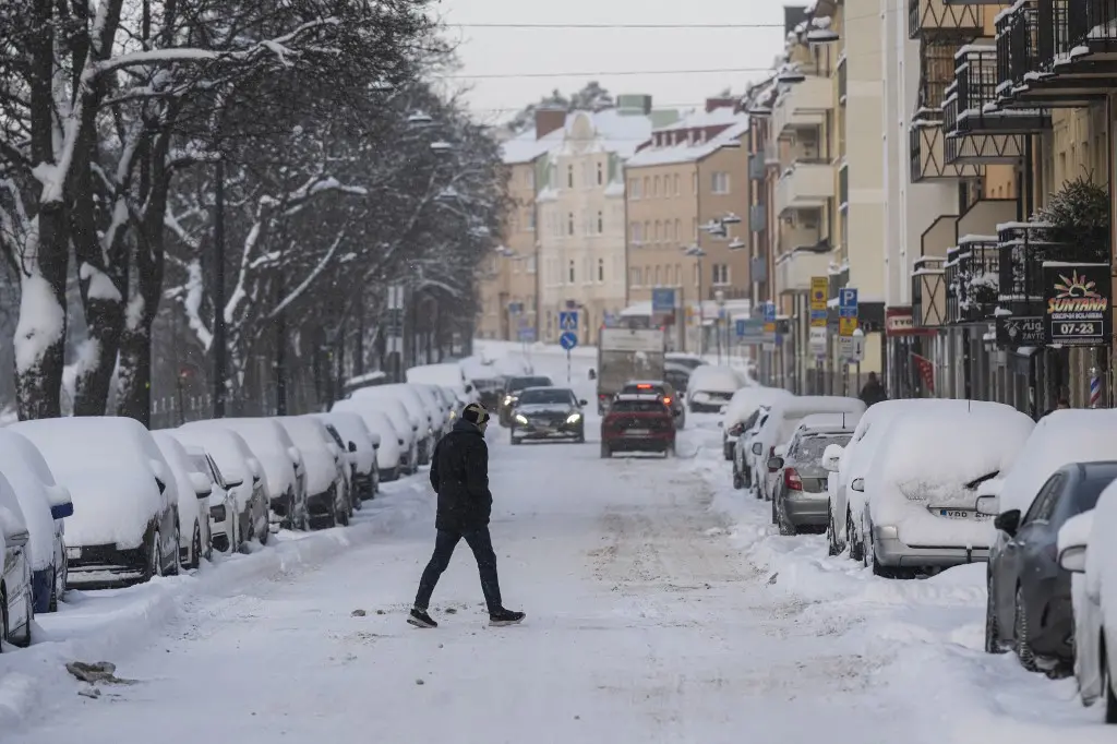 Pessoa caminha em rua coberta por neve em cidade na Suécia