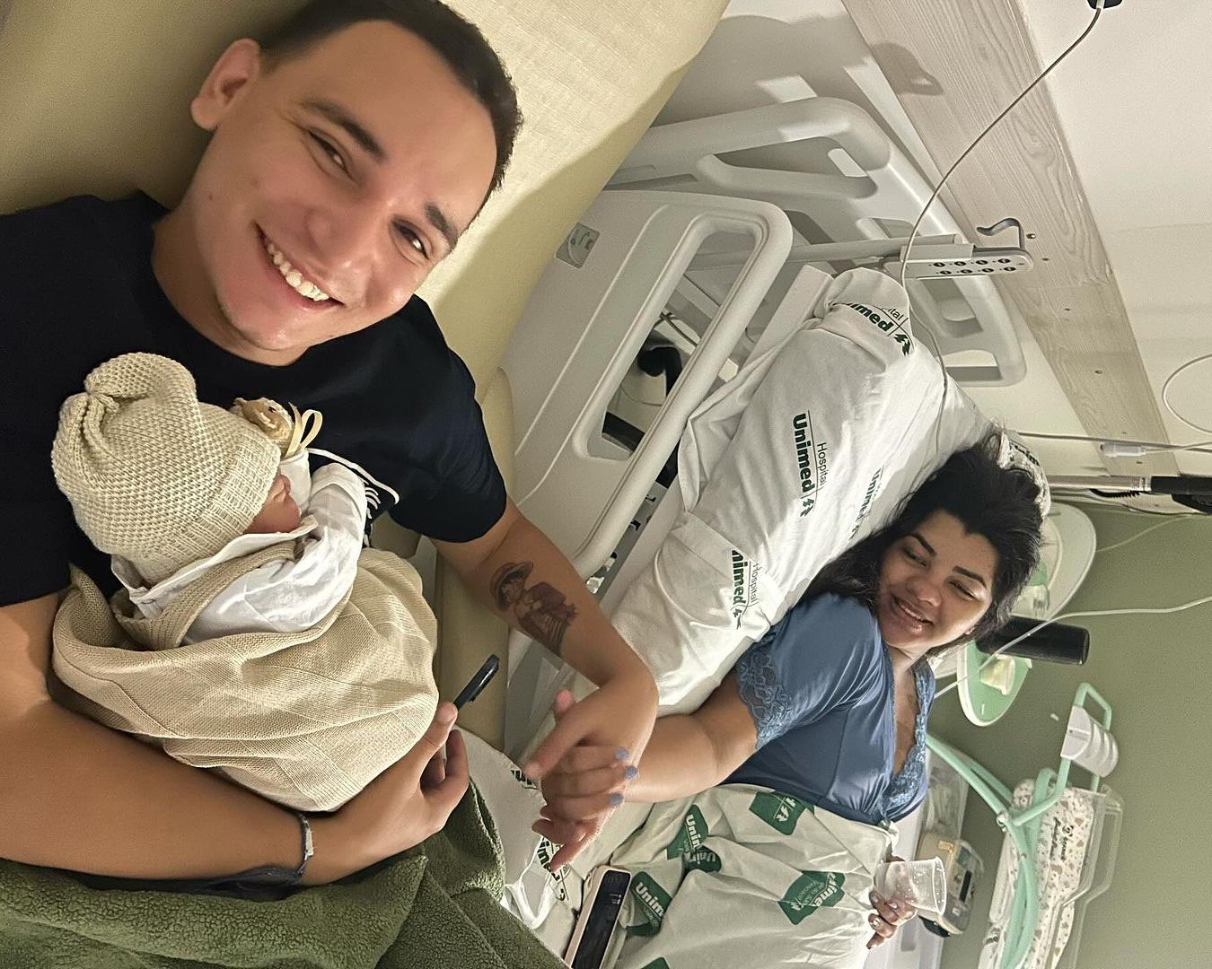 João Gomes segurando o filho ao lado de Ary Mirelle em internação no hospital
