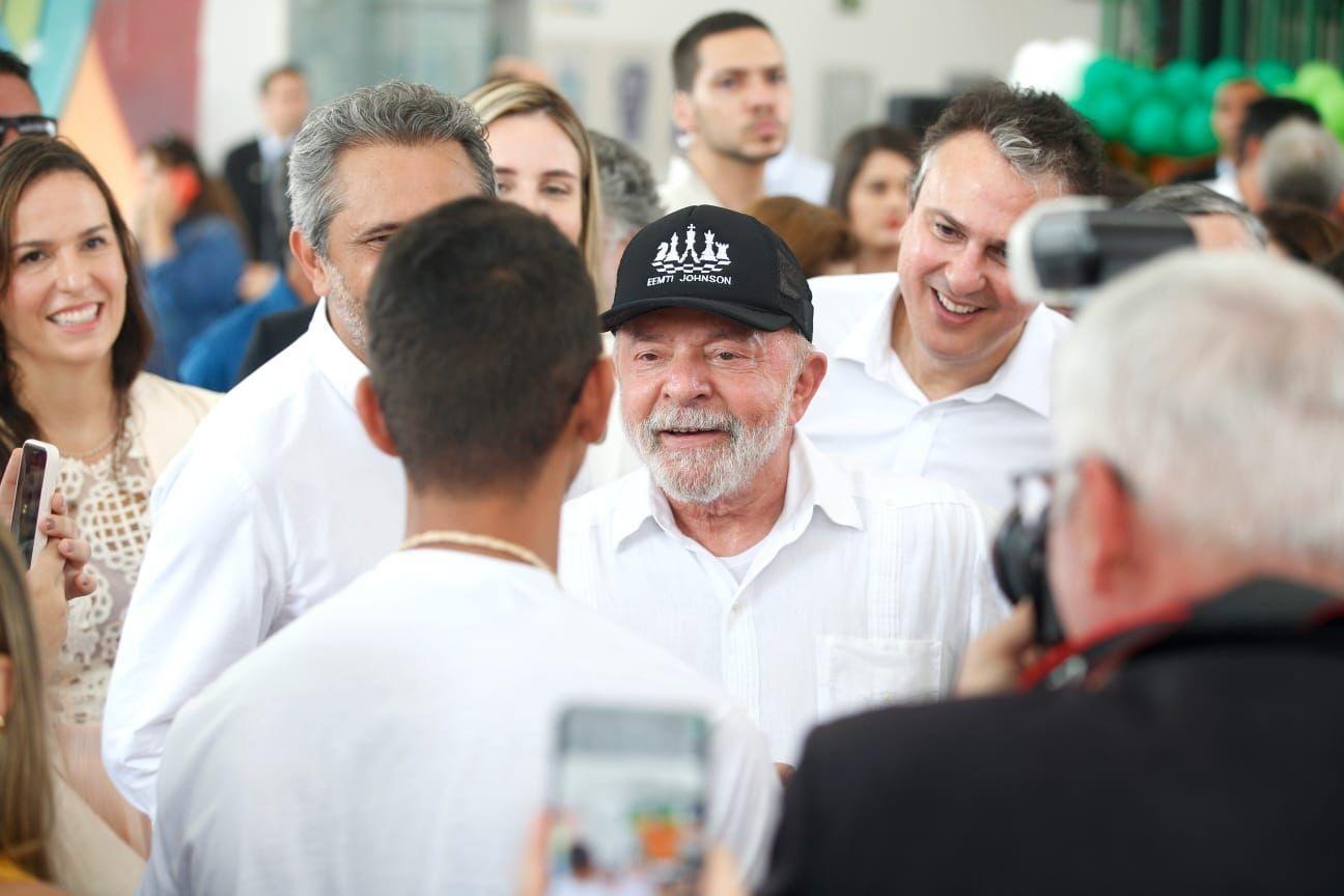Lula com camisa de botão branca e boné preto interage com adolescentes de escola de tempo integral