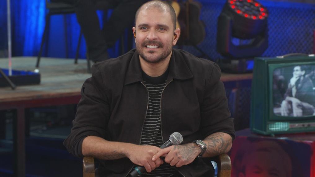 Cantor Diogo Nogueira em programa na TV segurando um microfone