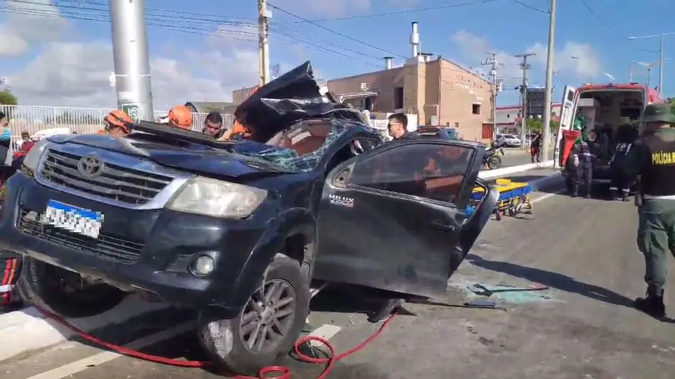 Carro Toyota Hilux no canteiro central com o teto afundado após colisão com poste