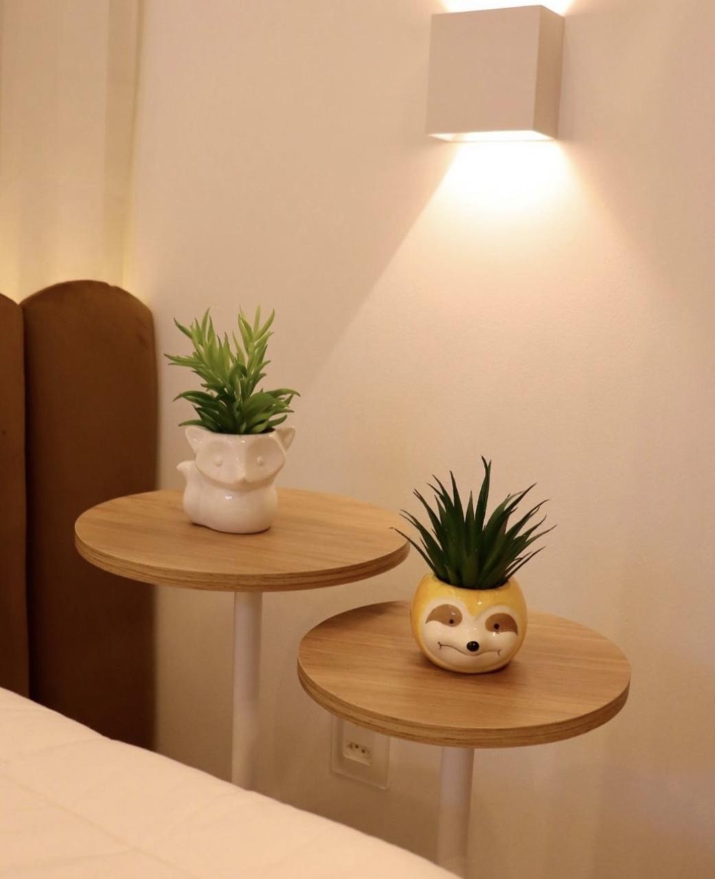 Arandela quadrada fixada na parede do quarto, perto da mesa de cabeceira. Luz de destaque pode transformar o seu ambiente