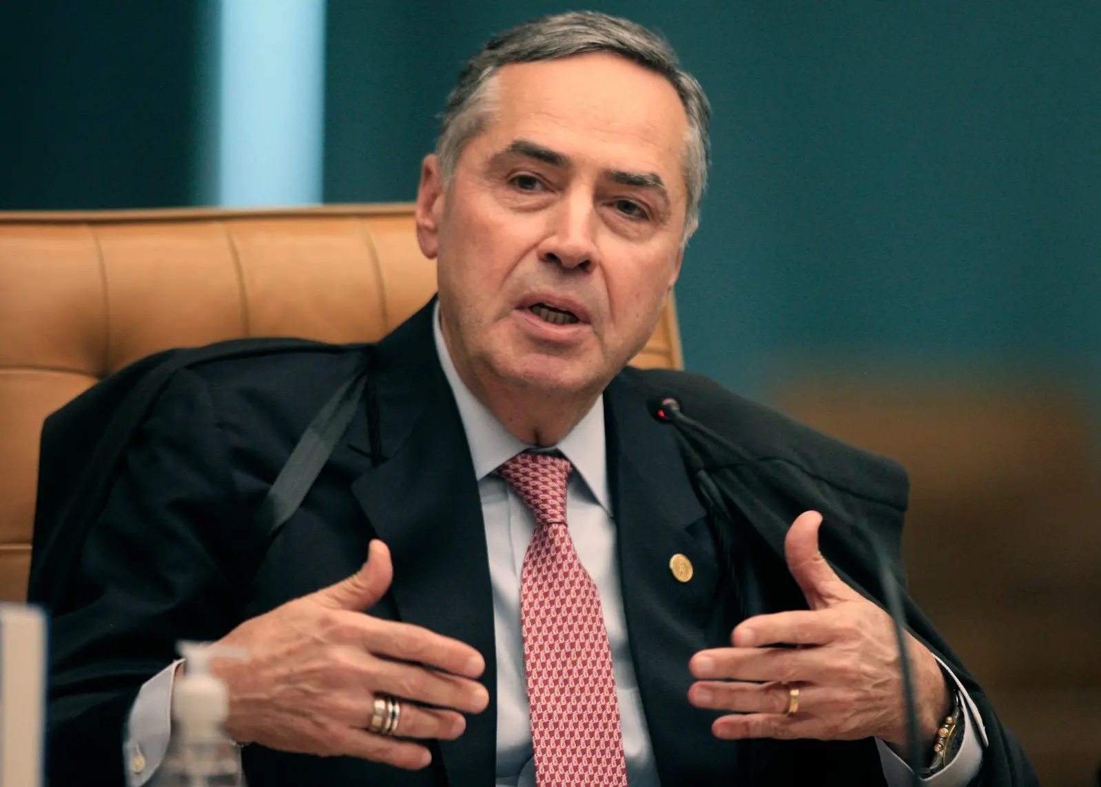 Luís Roberto Barroso é um homem branco e de cabelos grisalhos. Na foto, ele está gesticulando enquanto fala