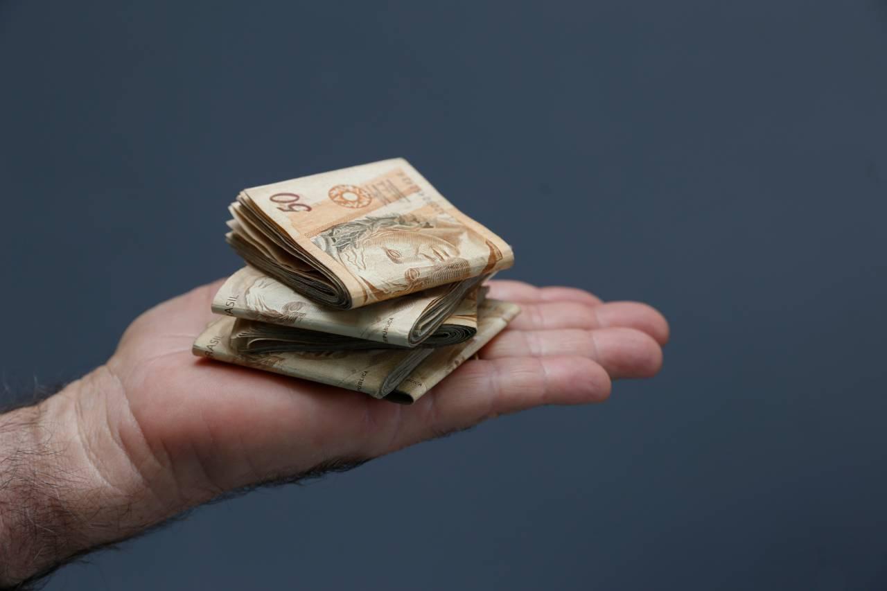 Mão segurando notas de Real