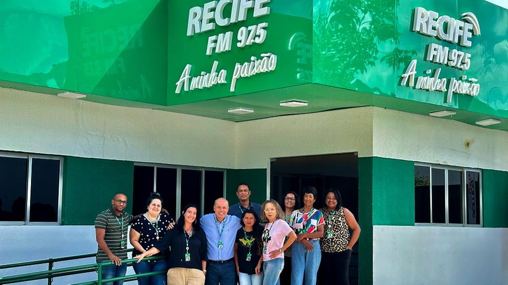 Fachada da Recife FM, com a equipe da emissora reunida em frente