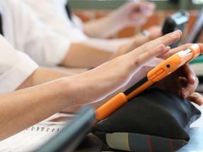 Jovens utilizam equipamento eletrônico na escola