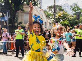 Menina negra e menina branca com confetes de carnaval na rua