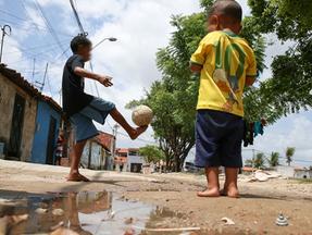 Crianças brincam em rua com esgoto