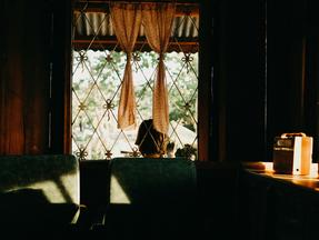 Janela gradeada com cortina e rádio na mesa ao lado