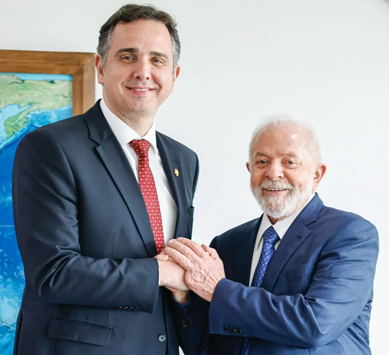 Rodrigo Pacheco e Lula de mãos dadas. Os dois usam terno e estão sorrindo para a foto