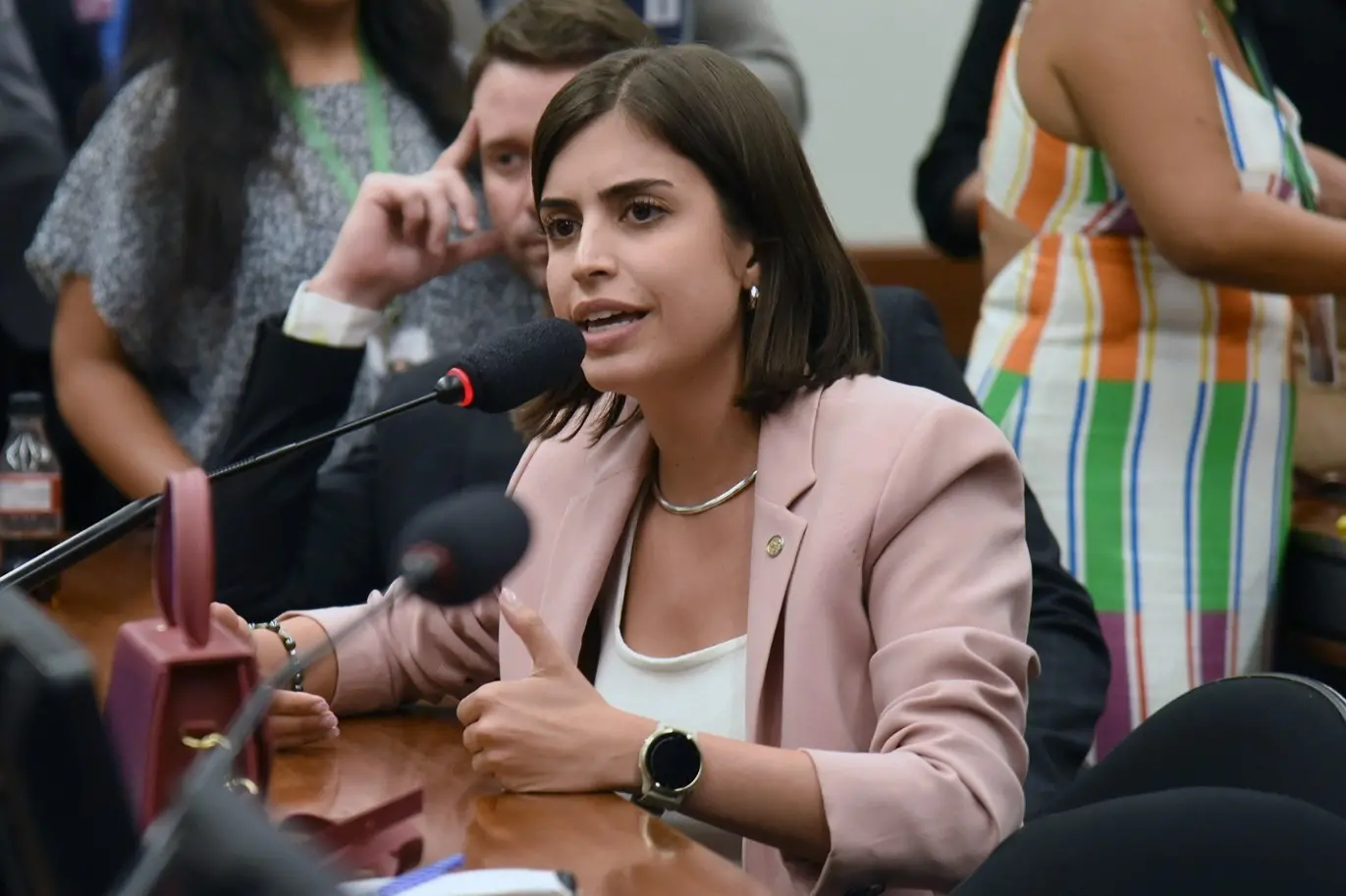 Tabata Amaral é uma mulher branca de cabelo médio liso e castanho. Na foto, ela está discursando. Usa blusa branca e blazer rosé