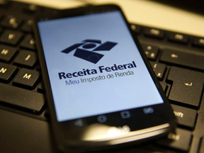 Celular sobre teclado mostrando o app da Receita Federal