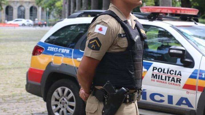 Policial militar ao lado de viatura da Polícia de Minas Gerais
