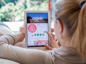Mulher olhando o aplicativo Airbnb em tablet