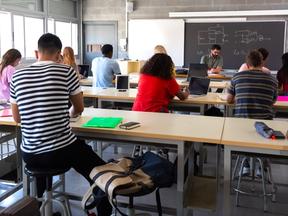 Vista traseira de um grupo de estudantes multirraciais do ensino médio em sala de aula usando laptops enquanto o professor marca os exames. Inscrições para o Fies começam nesta terça-feira (12); saiba como participar