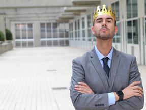 Homem de terno com atitude arrogante e uma coroa de rei na cabeça