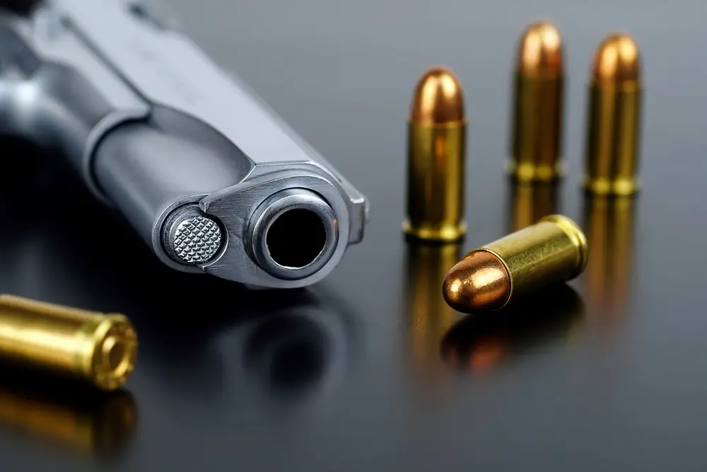 Revólver e munições dispostos em cima de uma mesa