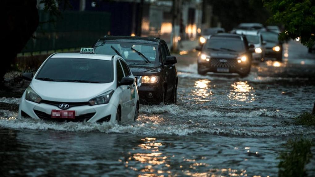 carros andando em rua alagada por chuva em Fortaleza