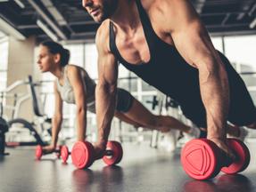 Imagem mostra homem e mulher se exercitando em academia, focando em músculo. Saiba o que é albumina e se ela é melhor que whey protein para ganho de massa muscular