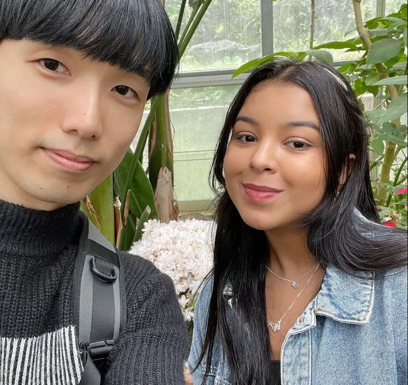 Yang e Luisa posam para foto próximo a plantas