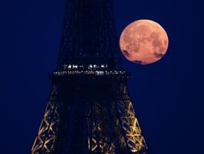 fotografia da Lua Cheia Rosa vista atrás da Torre Eiffel, em Paris