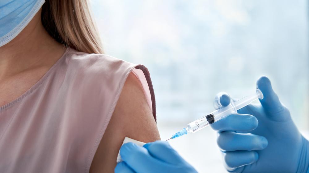 Pessoa aplica vacina no braço de outra