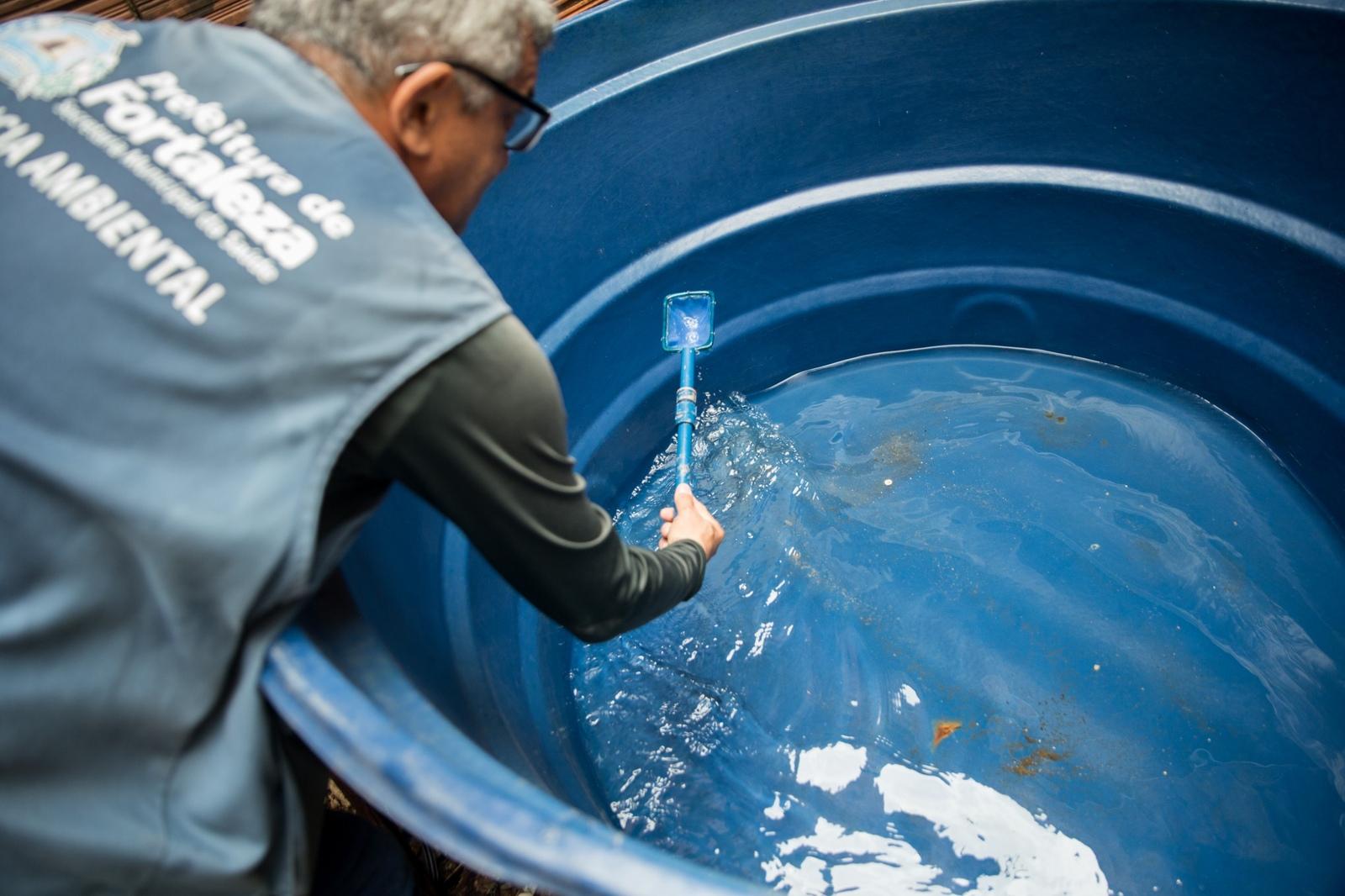 Agente de endemias busca larvas de mosquito da dengue em caixa d'água