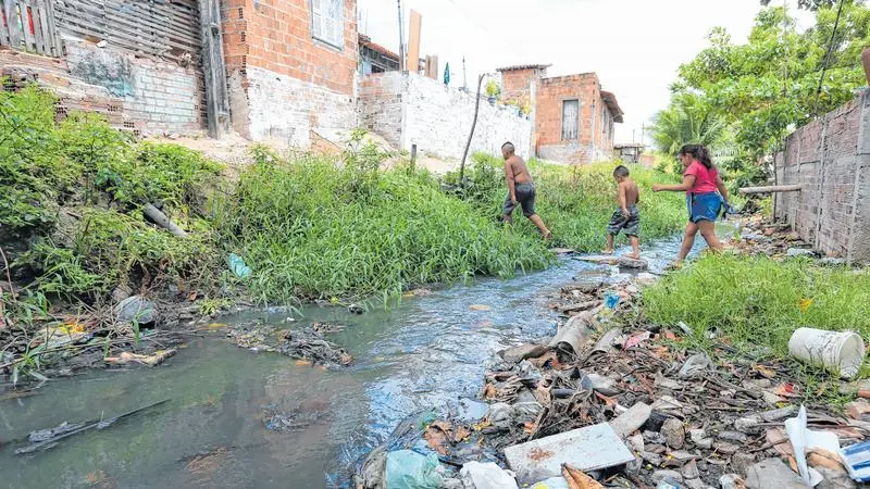 imagem de uma área de risco com córrego de lama e uma pessoa caminhando próximo