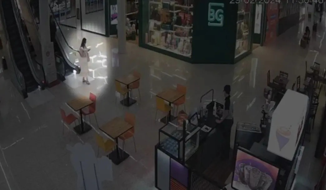 Imagem de câmera de segurança mostra Anic caminhando olhando o celular em um shopping