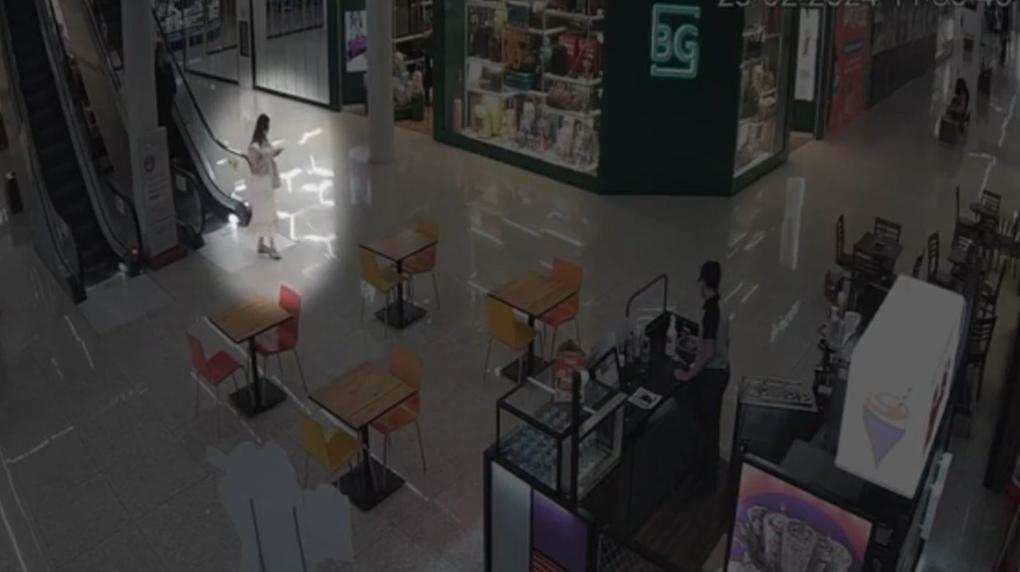 Imagem de câmera de segurança mostra Anic caminhando olhando o celular em um shopping