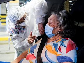 Idosa recebe reforço da vacina contra a Covid-19 dentro de um carro