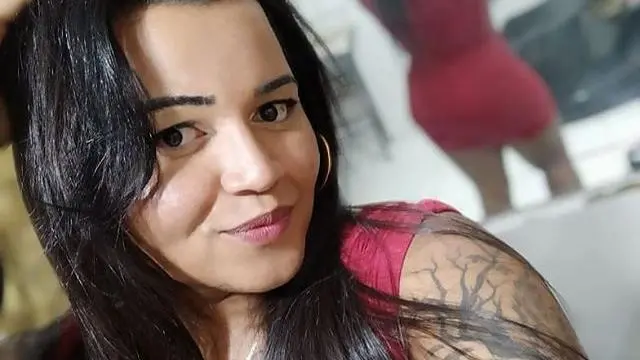 Selfie de Samylla. Ela era uma mulher de cabelos pretos, lisos, e tinha o braço tatuado