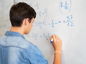 Estudante escreve fórmulas matemáticas na lousa