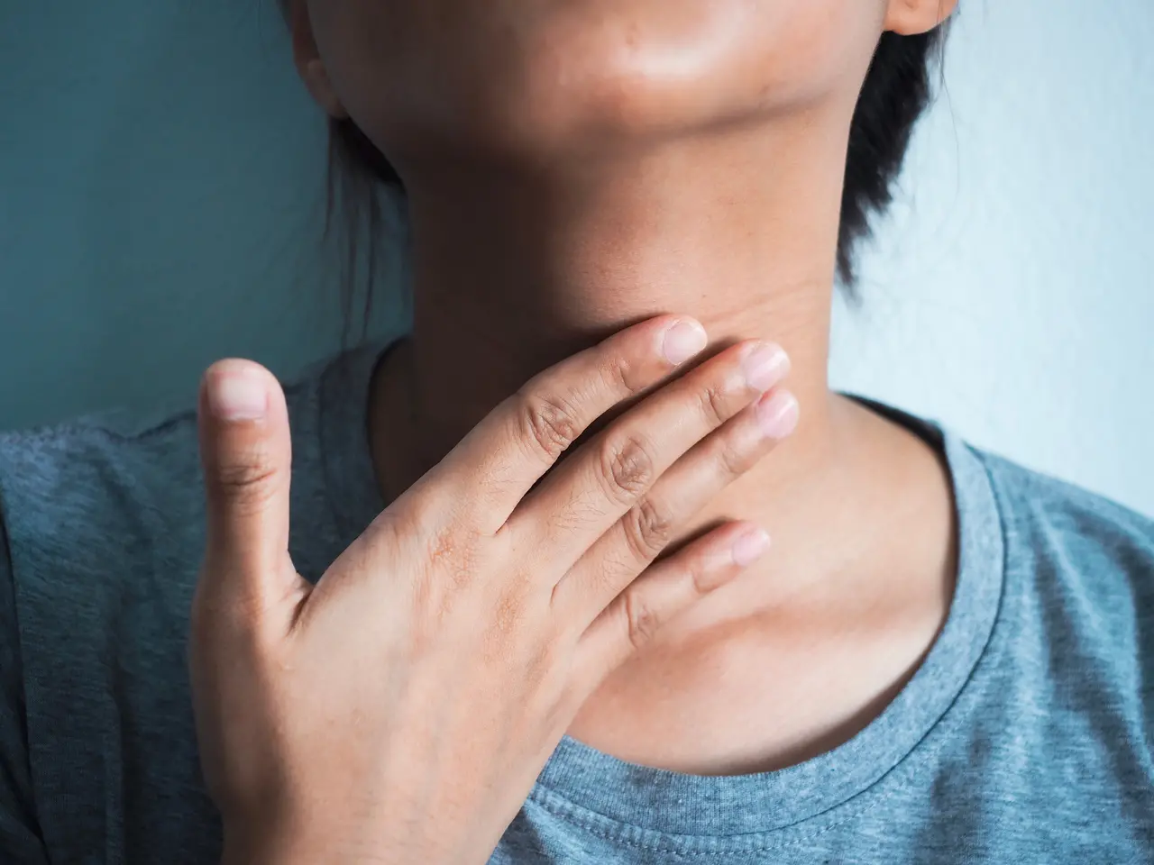 Mulher com mão no pescoço, ilustrando uma dor de garganta. Bala de gengibre é bom para a garganta? Veja receita, benefícios e para que serve a planta