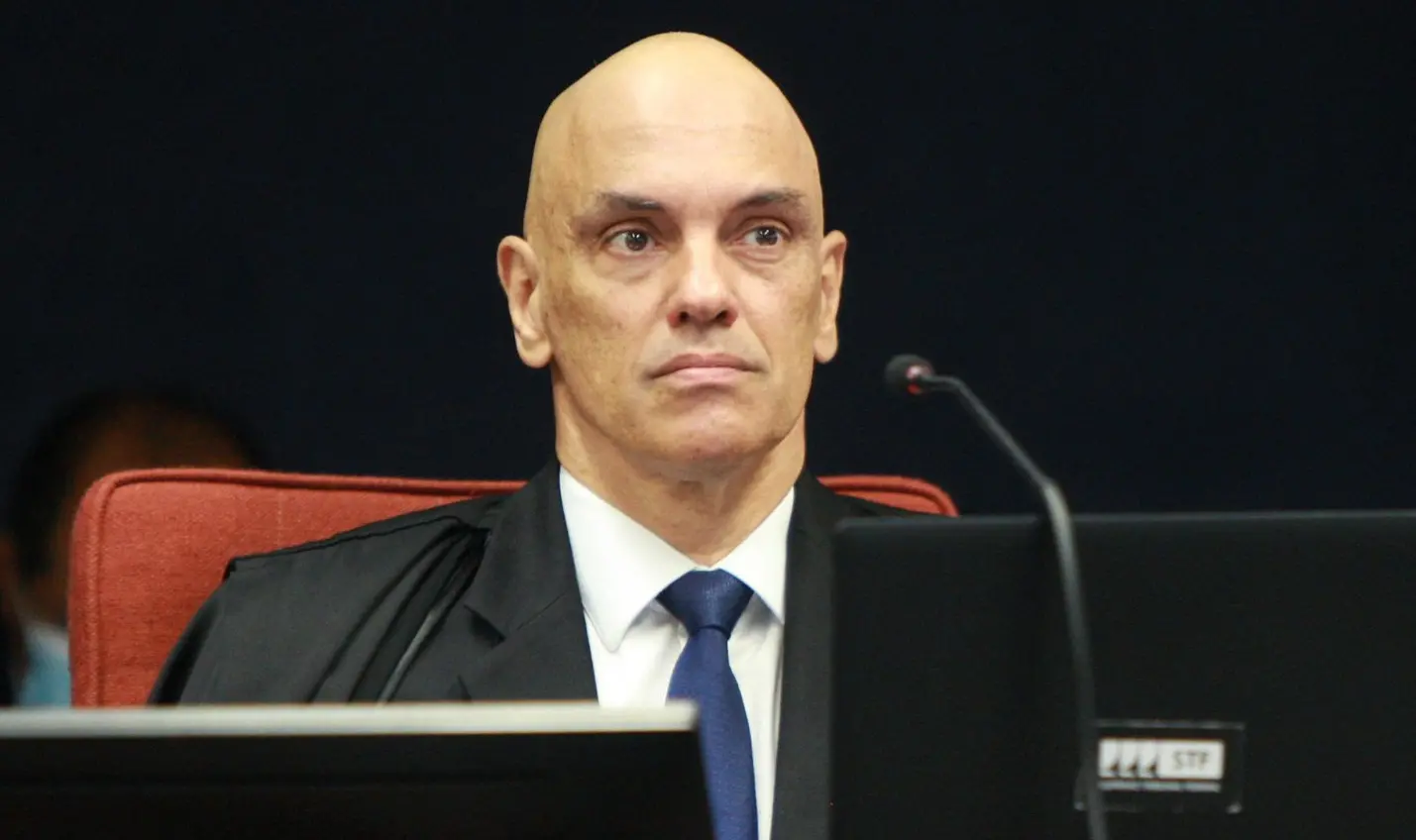 Alexandre de Moraes é um homem branco e careca. Na foto, ele está sério e usa terno preto com camisa branca e gravata azul