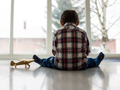 Criança sozinha sentada ao lado de um brinquedo