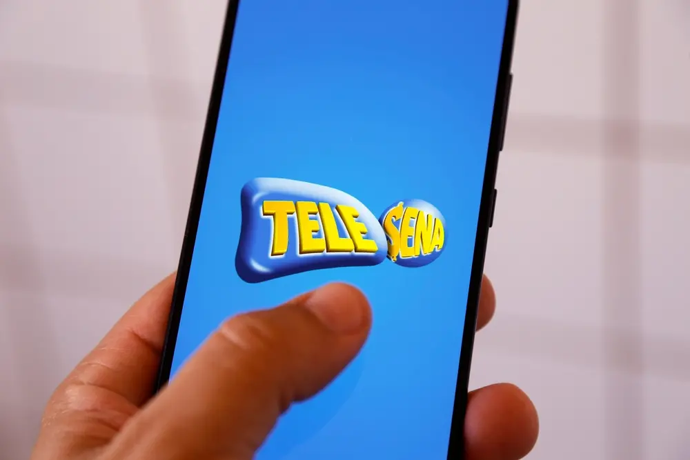 Mão segura celular aberto no app da Tele Sena