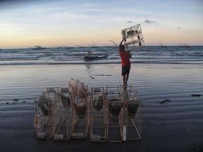 Pescador carregando gaiola de pesca