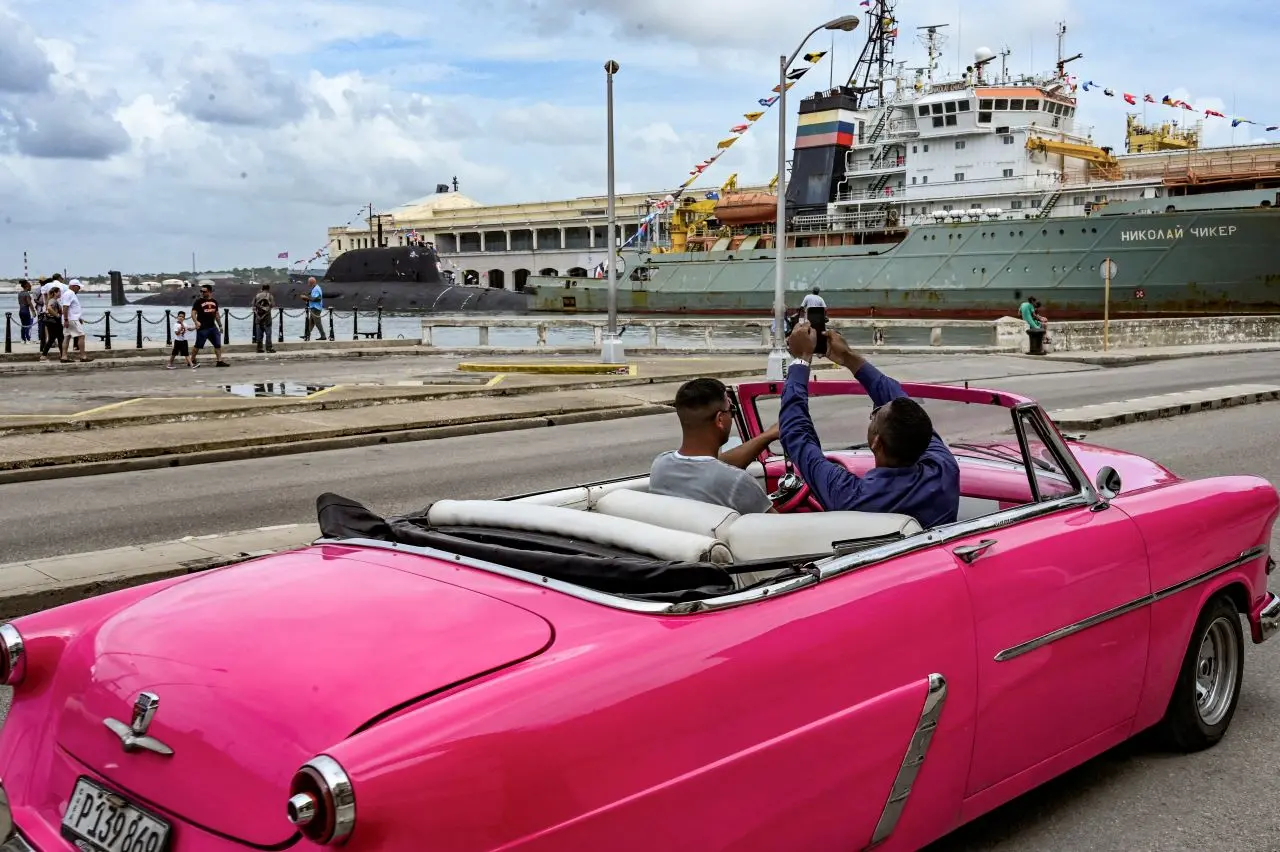 pessoas em carro rosa fotografando embarcações russas em cuba