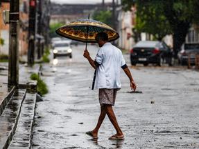 Homem caminha com guarda-chuva na mão