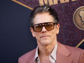 ator kevin bacon usando óculos escuros e terno rosa