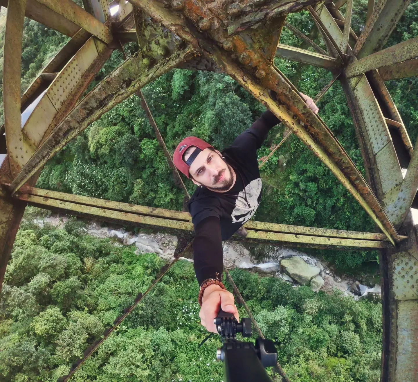 Homem de boné vermelho em cima de estruturas de ferro suspensas