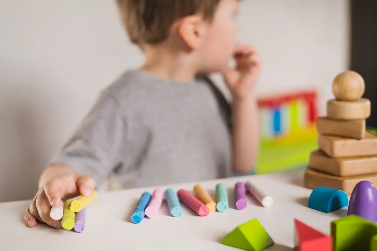 Criança autista brinca com giz de cera colorido