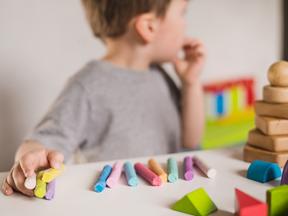 Criança autista brinca com giz de cera colorido