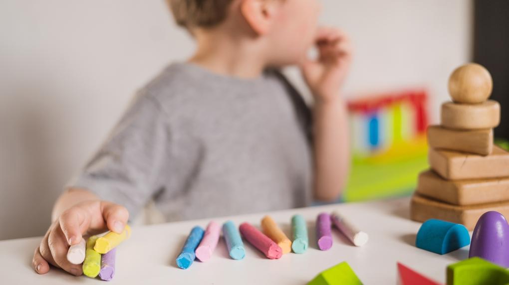 Criança autista brinca com giz de cera colorido
