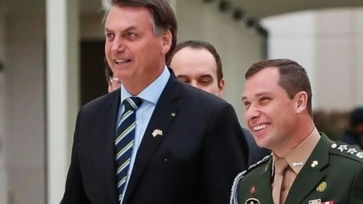 Bolsonaro e Mauro Cid rindo enquanto caminham