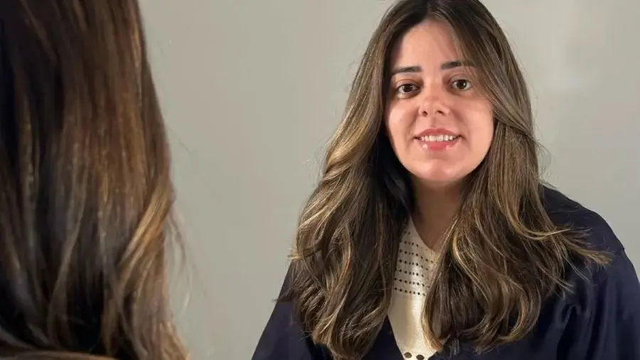 Juliana Perdomo é uma mulher branca de longos cabelos castanhos ondulados