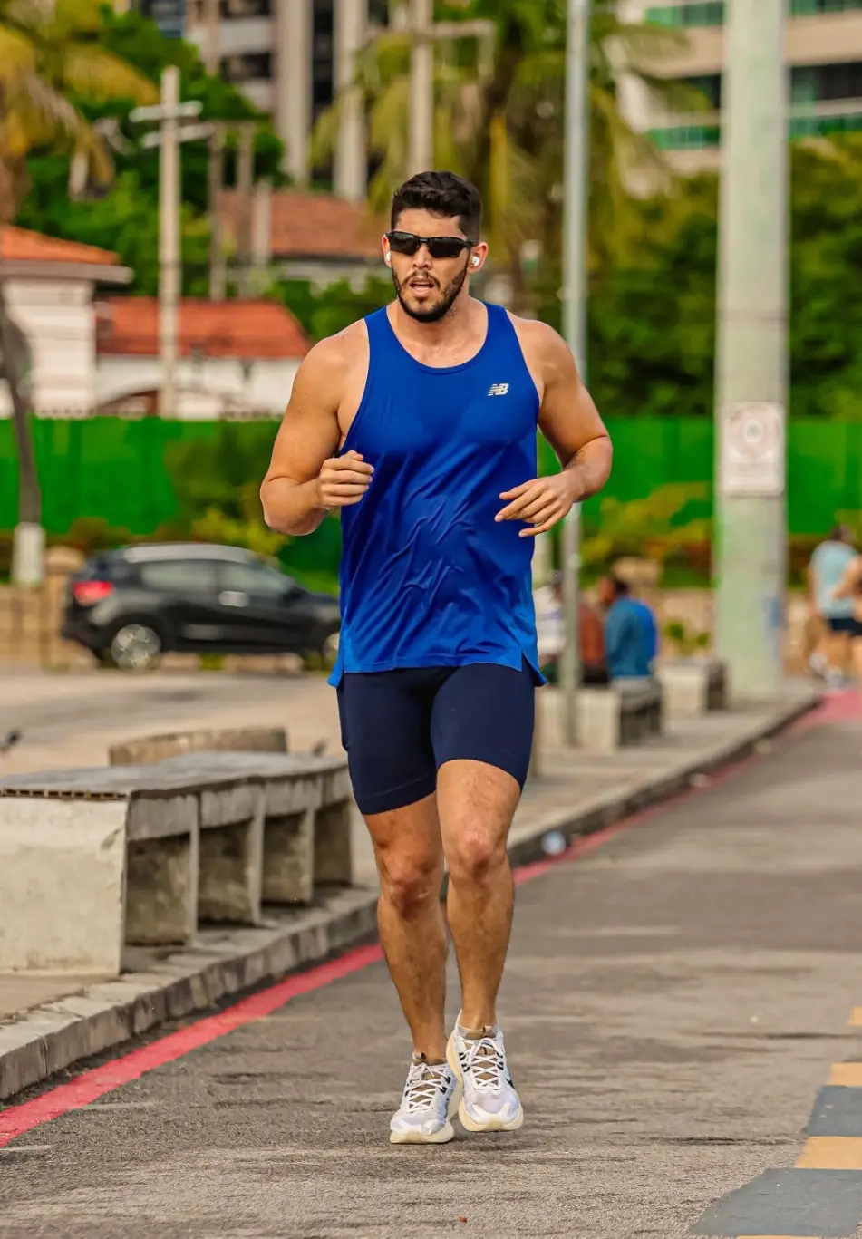 Darlyson correndo na rua. Ele é um homem alto e está usando bermuda e camiseta