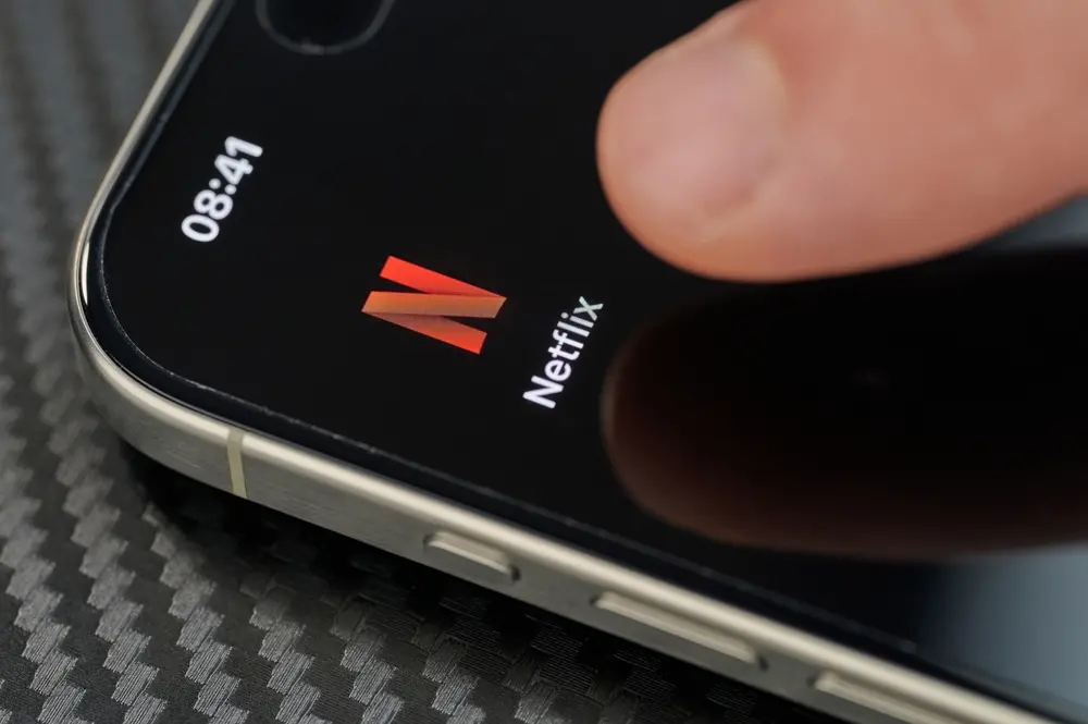 Dedo clica em aplicativo da Netflix em iPhone